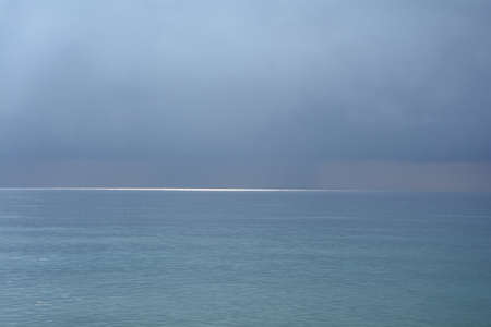 A glimpse of the sun on the sea surface after a thunderstormの写真素材