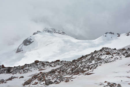 A mountain range surrounded by clouds and shadowsの写真素材