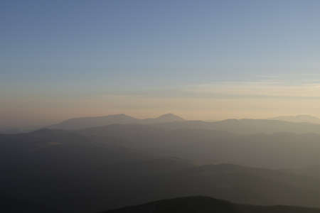 Sunset over a chain of old mountains stretching away to the horizonの写真素材