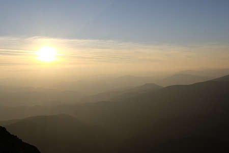 Sunset over a chain of old mountains stretching away to the horizonの写真素材