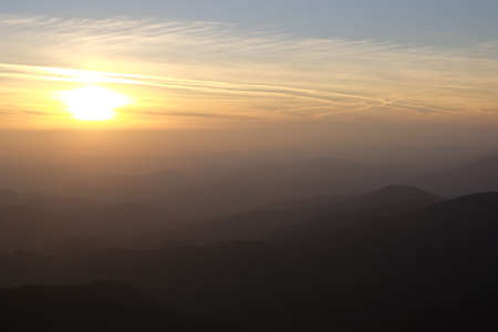 Sunset over a chain of old mountains stretching away to the horizonの写真素材