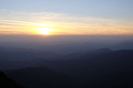 Sunset over a chain of old mountains stretching away to the horizonの写真素材