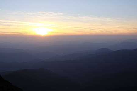 Sunset over a chain of old mountains stretching away to the horizonの写真素材