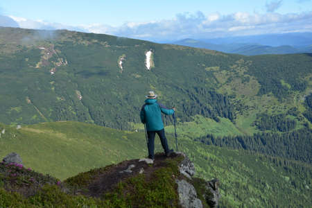 A traveler in a hat stands on the edge of a cliff.の写真素材