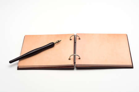 an open notebook with a cover made of natural materials and an old fountain penの写真素材