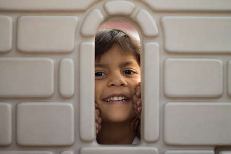 Cute brunette girl showing her smiling face in the window of a castleの写真素材