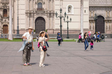 LIMA, PERU - AUG 29TH 2015: Couple of Japanese tourists taking pictures in the Plaza de Armas downtown Lima.のeditorial素材
