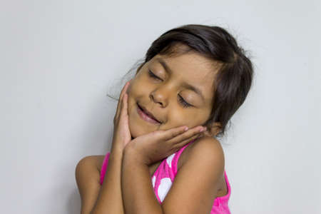 Cute smiling girl with her hands on her faceの写真素材