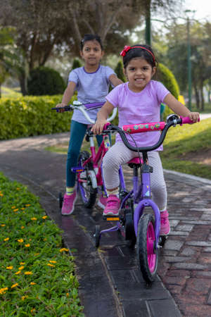 Sisters riding bicycle in a city parkの写真素材