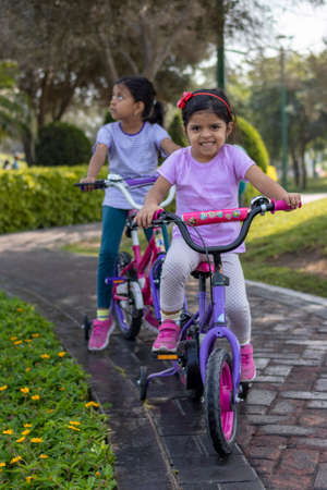 Sisters riding bicycle in a city parkの写真素材