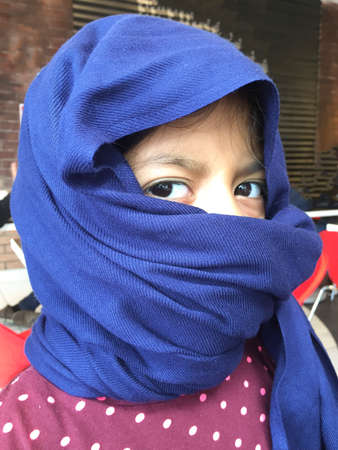 A girl plays with a blue turban on her headの写真素材