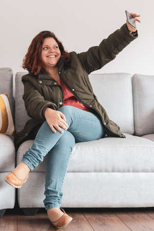 Woman takes a selfie from a sofaの写真素材