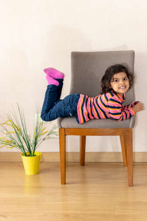 Cute little girl next to a chair at homeの写真素材