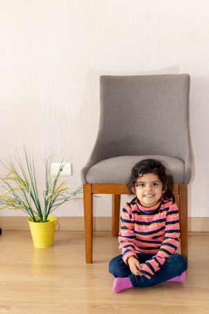 Cute little girl next to a chair at homeの写真素材