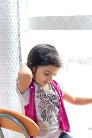 Cute little girl sitting on living room chairの写真素材
