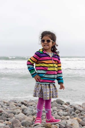 Cute little girl with colorful sweater walking on the beachの写真素材