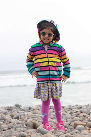 Cute little girl with colorful sweater walking on the beachの写真素材
