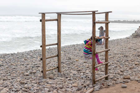Cute little girl with colorful sweater playing on the beachの写真素材