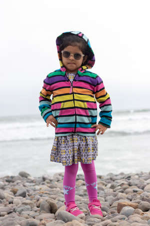 Cute little girl with colorful sweater walking on the beachの写真素材