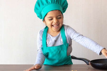 Cute little girl cooking with her frying pan in the kitchenの写真素材