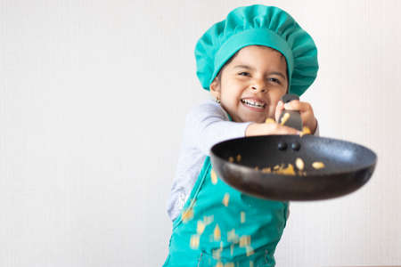 Cute little girl cooking with her frying pan in the kitchenの写真素材