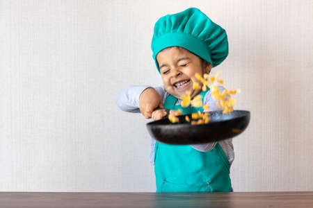 Cute little girl cooking with her frying pan in the kitchenの写真素材
