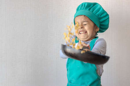 Cute little girl cooking with her frying pan in the kitchenの写真素材