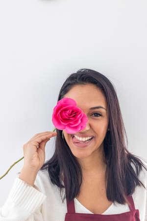 Cute smiling brunette playing with a red roseの写真素材