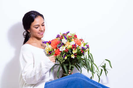 Cute brunette woman enjoying her bouquet of flowersの写真素材