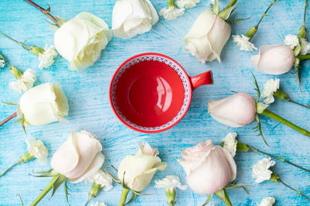 Cup of coffee surrounded by white rosesの写真素材