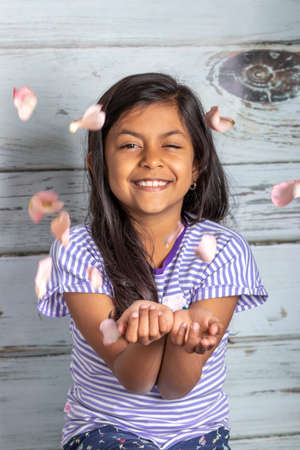 Cute brunette girl playing with pink rose petalsの写真素材