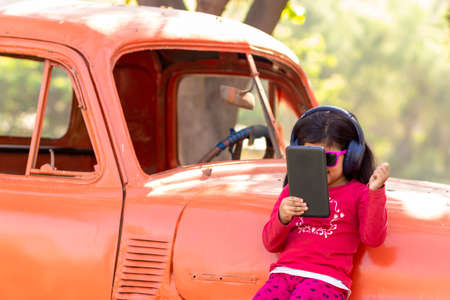 Little girl listening to music on the tablet with her headphones in the truck carの写真素材