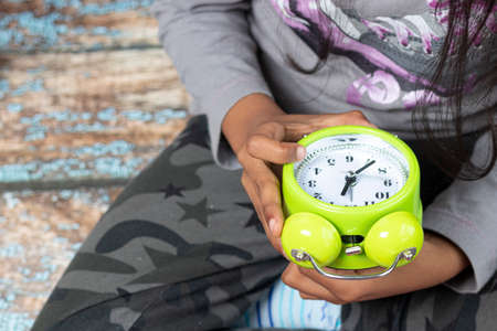 Little girl waking up with an alarm clockの写真素材