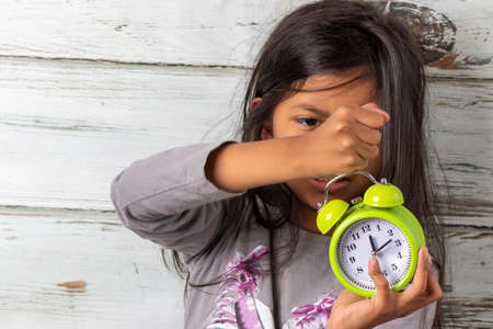 Little girl waking up with an alarm clockの写真素材