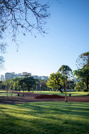 View of a beautiful park with green areas and reddish soil, located within the cityの写真素材