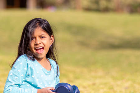 Little girl listening to music on the smartphone with her headphones in the parkの写真素材