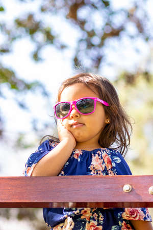 Cute little girl with pink sunglasses and hands on her face.の写真素材