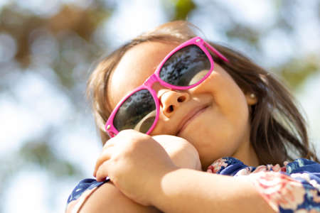 Cute little girl with pink sunglasses and hands on her face.の写真素材
