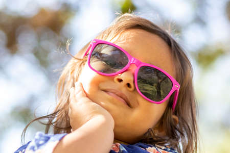 Cute little girl with pink sunglasses and hands on her face.の写真素材