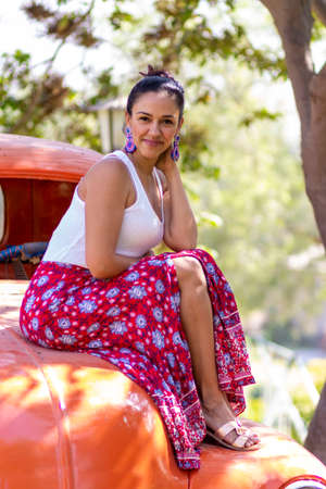 Cute latin woman posing on an orange carの写真素材