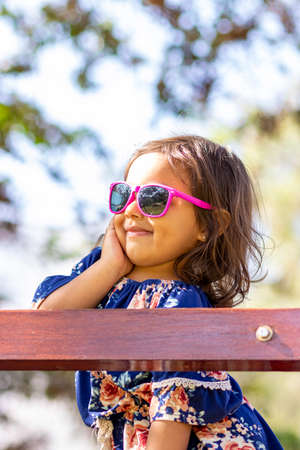 Cute little girl with pink sunglasses and hands on her face.の写真素材