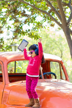 Little girl listening to music on the tablet with her headphones in the truck carの写真素材