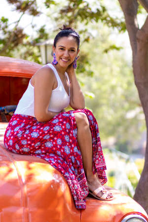 Cute latin woman posing on an orange carの写真素材