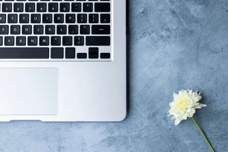 Home office table desk workspace with laptop decorated with white dahlia flowerの写真素材