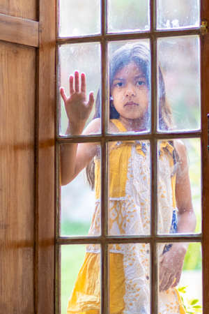 Brunette girl behind wooden and glass doorの写真素材