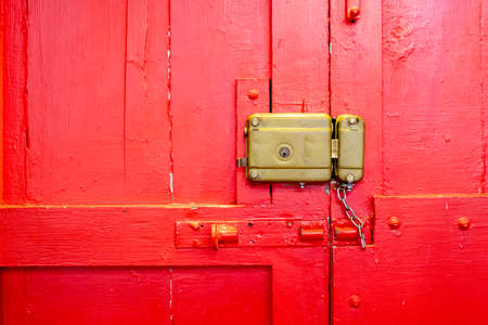 Old red gate with manual lockの写真素材