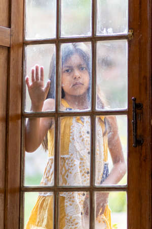 Brunette girl behind wooden and glass doorの写真素材