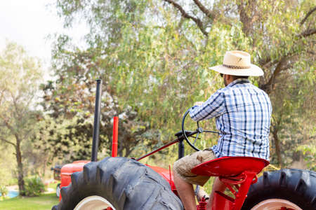 Handsome man with sunglasses driving the tractor to work on the farmの写真素材