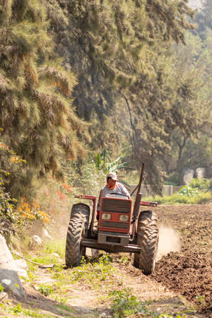 Man preparing the land for harvest with the tractor on the farm