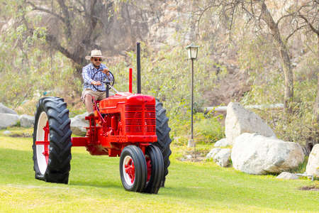 Handsome man with sunglasses driving the tractor to work on the farmの写真素材